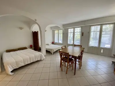 a bedroom with a bed and a table and chairs at Cannes proche croisette - Studio balcon vue jardin in Cannes