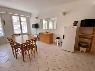 a kitchen and dining room with a table and a refrigerator at Cannes proche croisette - Studio balcon vue jardin in Cannes