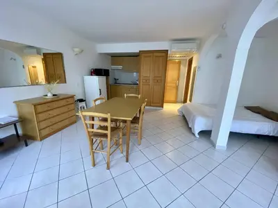 a kitchen and dining room with a table and a bed at Cannes proche croisette - Studio balcon vue jardin in Cannes