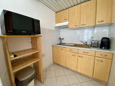 a small kitchen with a microwave and a sink at Cannes proche croisette - Studio balcon vue jardin in Cannes