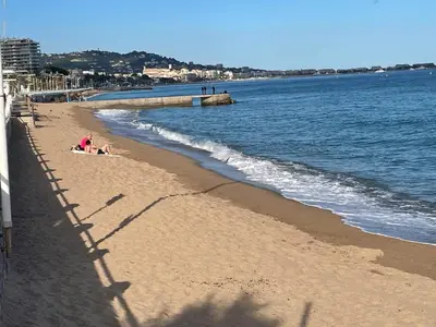 a beach with two people sitting on the sand at Résidence Palme d'Azur Cannes La Bocca in Cannes