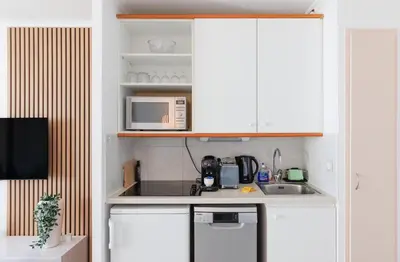 a small kitchen with white cabinets and a microwave at Holiday Paradise in Cannes