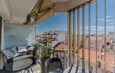 a balcony with a couch and a view of the city at Le Mimosas - Studio Cannes centre - Vue mer Terrasse WIFI climatisation in Cannes