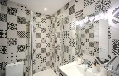 a bathroom with black and white tiles on the wall at Le Mimosas - Studio Cannes centre - Vue mer Terrasse WIFI climatisation in Cannes