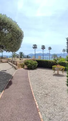 a walkway in a park with benches and trees at La Dolce Vita de Cannes: Luxury city center apartement, beautiful View in Cannes