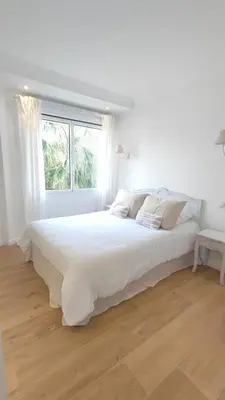 a white bedroom with a large white bed with a window at La Dolce Vita de Cannes: Luxury city center apartement, beautiful View in Cannes
