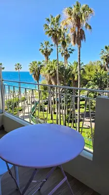 a white table on a balcony with palm trees and the ocean at La Dolce Vita de Cannes: Luxury city center apartement, beautiful View in Cannes