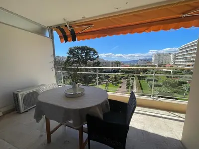 a table and chairs in a room with a large window at Croisette and beaches. View on gardens and sea. in Cannes