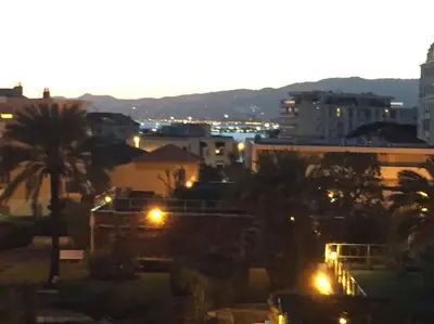 a city with buildings and palm trees at night at Croisette and beaches. View on gardens and sea. in Cannes