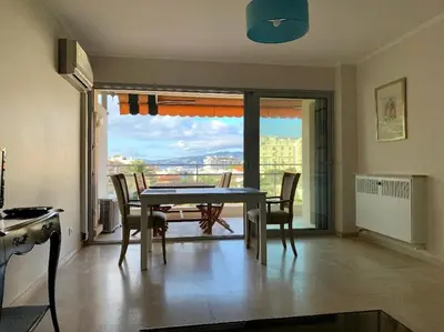 a dining room with a table and chairs and a balcony at Croisette and beaches. View on gardens and sea. in Cannes