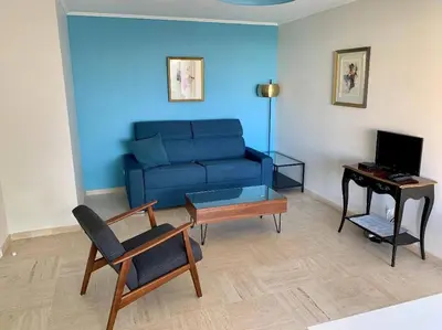a living room with a blue couch and a table at Croisette and beaches. View on gardens and sea. in Cannes