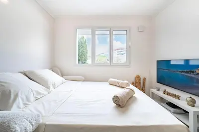 a white bedroom with a bed and a flat screen tv at Studio Banane 2 min croisette mitoyen Martinez in Cannes