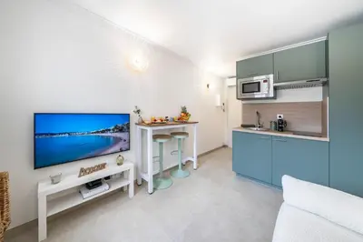 a living room with a tv and a kitchen at Studio Banane 2 min croisette mitoyen Martinez in Cannes