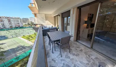 a balcony with a table and a view of a tennis court at LACOUR7 Palmes dProperties in Cannes
