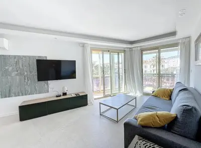 a living room with a blue couch and a flat screen tv at Modern 2 Bedroom in the Heart of Cannes in Cannes