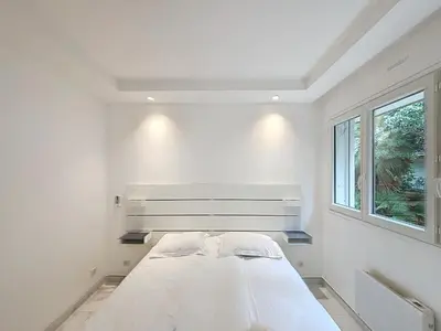 a white bedroom with a bed and a window at Résidence Lacour in Cannes