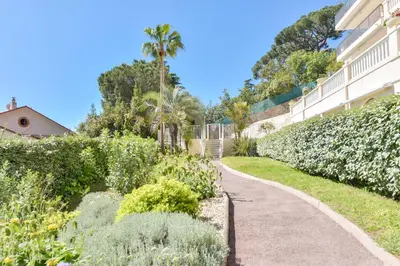 a path in a garden next to a building at 1-Br apartment calm sea view pool and parking garage in Cannes