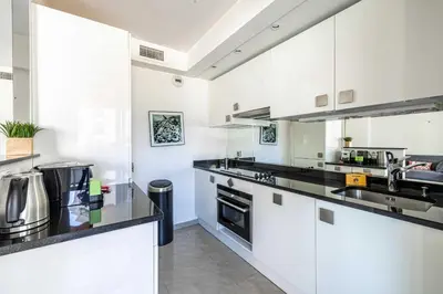 a kitchen with white cabinets and black counter tops at Bright apartment near the Croisette - Cannes in Cannes