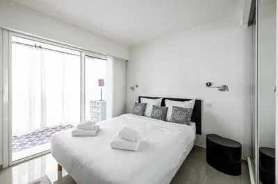 a white bedroom with a large bed and a large window at Bright apartment near the Croisette - Cannes in Cannes