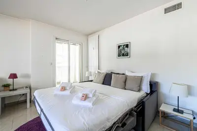 a white bedroom with a large bed with two towels at Bright apartment near the Croisette - Cannes in Cannes