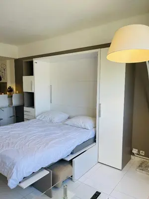 a large white bed in a room with a lamp at Studio proche centre FARN4 in Cannes