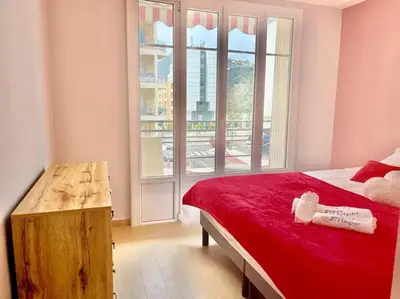 a bedroom with a red bed and a large window at Mérimée in Le Cannet