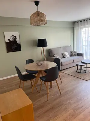 a living room with a table and chairs and a couch at Cannes Appartement neuf tout confort in Le Cannet