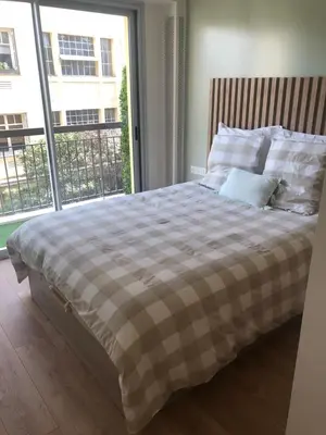 a bed in a room with a large window at Cannes Appartement neuf tout confort in Le Cannet