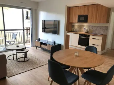 a living room with a table and chairs and a kitchen at Cannes Appartement neuf tout confort in Le Cannet