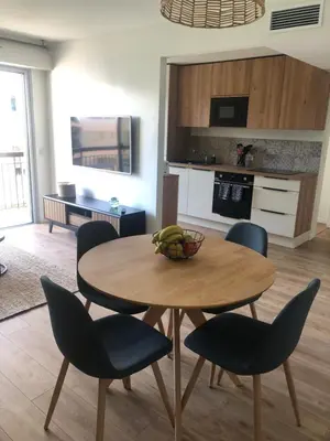 a table with chairs and a bowl of fruit on it in a kitchen at Cannes Appartement neuf tout confort in Le Cannet