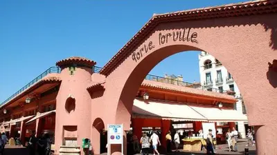 a building with an arch with people walking in front of it at 2 pièces Cannes centre in Cannes