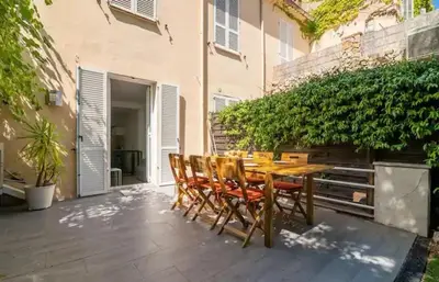 a wooden table and chairs on a patio at BEAU REZ DE JARDIN- Cannes Suquet - Clim- Calme - Lumineux- 15 minutes Palais des Festival in Cannes
