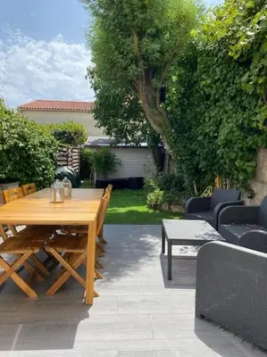 a wooden table and chairs in a backyard with a table and chairs at BEAU REZ DE JARDIN- Cannes Suquet - Clim- Calme - Lumineux- 15 minutes Palais des Festival in Cannes