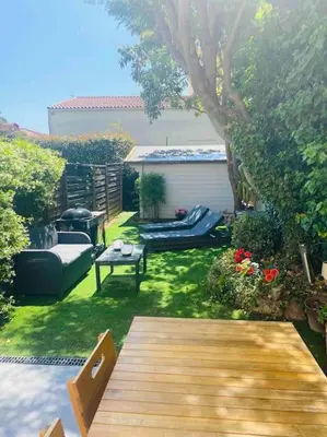 a garden with a wooden deck and chairs and a table at BEAU REZ DE JARDIN- Cannes Suquet - Clim- Calme - Lumineux- 15 minutes Palais des Festival in Cannes