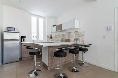 a kitchen with a counter and bar stools in it at BEAU REZ DE JARDIN- Cannes Suquet - Clim- Calme - Lumineux- 15 minutes Palais des Festival in Cannes