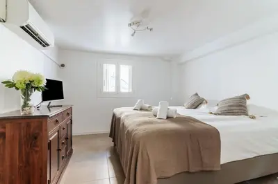 a white bedroom with a bed and a television at BEAU REZ DE JARDIN- Cannes Suquet - Clim- Calme - Lumineux- 15 minutes Palais des Festival in Cannes