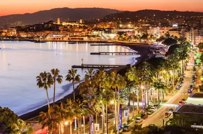 a city with palm trees and a river at night at Appartement 3P dans Maison Bourgeoise - 6 personnes - Vue Mer - Parking in Cannes