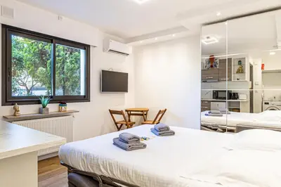 a white room with a bed and a kitchen at 4 BARON - Spacieux studio rénové quartier des Anglais in Cannes