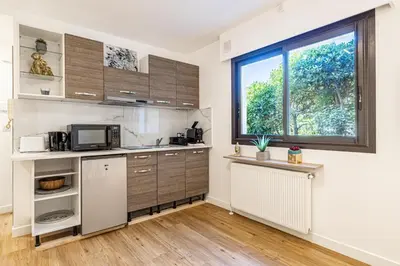 a kitchen with wooden cabinets and a window at 4 BARON - Spacieux studio rénové quartier des Anglais in Cannes