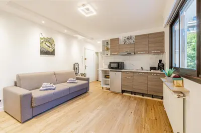 a living room with a couch and a kitchen at 4 BARON - Spacieux studio rénové quartier des Anglais in Cannes
