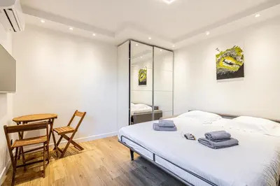a bedroom with a bed and a table and a chair at 4 BARON - Spacieux studio rénové quartier des Anglais in Cannes