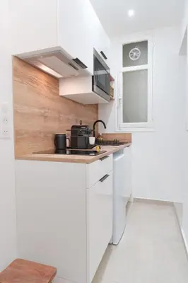 a white kitchen with a sink and a microwave at Le Bosquet - Quiet - Hypercentre - AC - Garden in Cannes