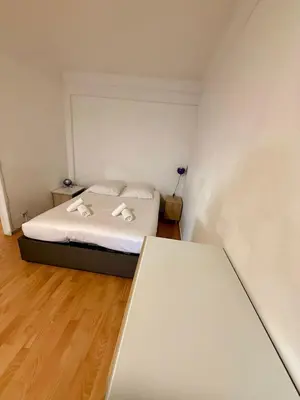 a small white bedroom with a bed and a table at Studio Vidal in the city center of Cannes with AC in Cannes