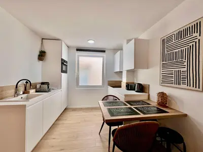 a kitchen with white cabinets and a table and chairs at C003 Cosy a 200 m du Palais plein centre Cannes in Cannes