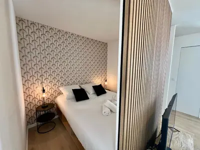 a bedroom with a large white bed with black pillows at C003 Cosy a 200 m du Palais plein centre Cannes in Cannes