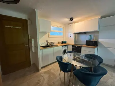 a kitchen with a glass table and two blue chairs at B023 Tres bel appartement proche de la mer a Cannes in Cannes