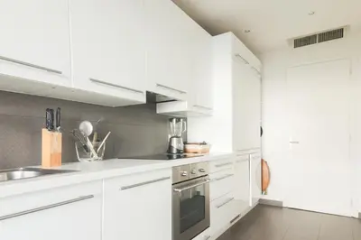 a white kitchen with white cabinets and a sink at Magnifique vue mer, grande terrasse et piscine in Cannes