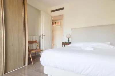 a bedroom with a white bed and a chair at Magnifique vue mer, grande terrasse et piscine in Cannes