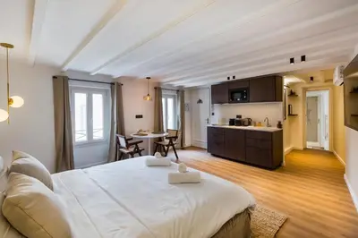 a bedroom with a large bed and a kitchen at Luxury suite Forville - Cannes center in Cannes