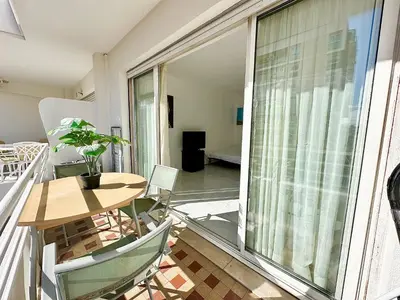 a balcony with a table and chairs and a large window at Alexendre 3 Elégant Studio Centre Cannes proche Palais des festivals in Cannes